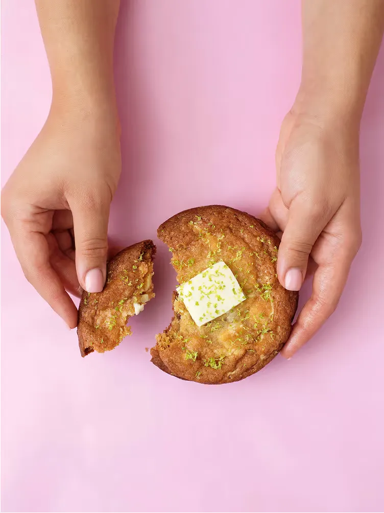 Händer bryter en cookie med vit choklad